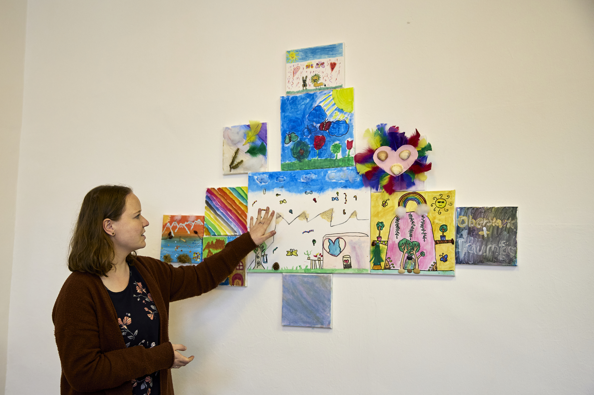 Ellen Sachsenmaier zeigt die Ergebnisse eines kunsttherapeutischen Angebots, bei dem die Kinder einen sicheren Ort malen sollten. An diesen Ort können sie sich gedanklich zurückziehen, wenn sie Stress oder Angst haben.